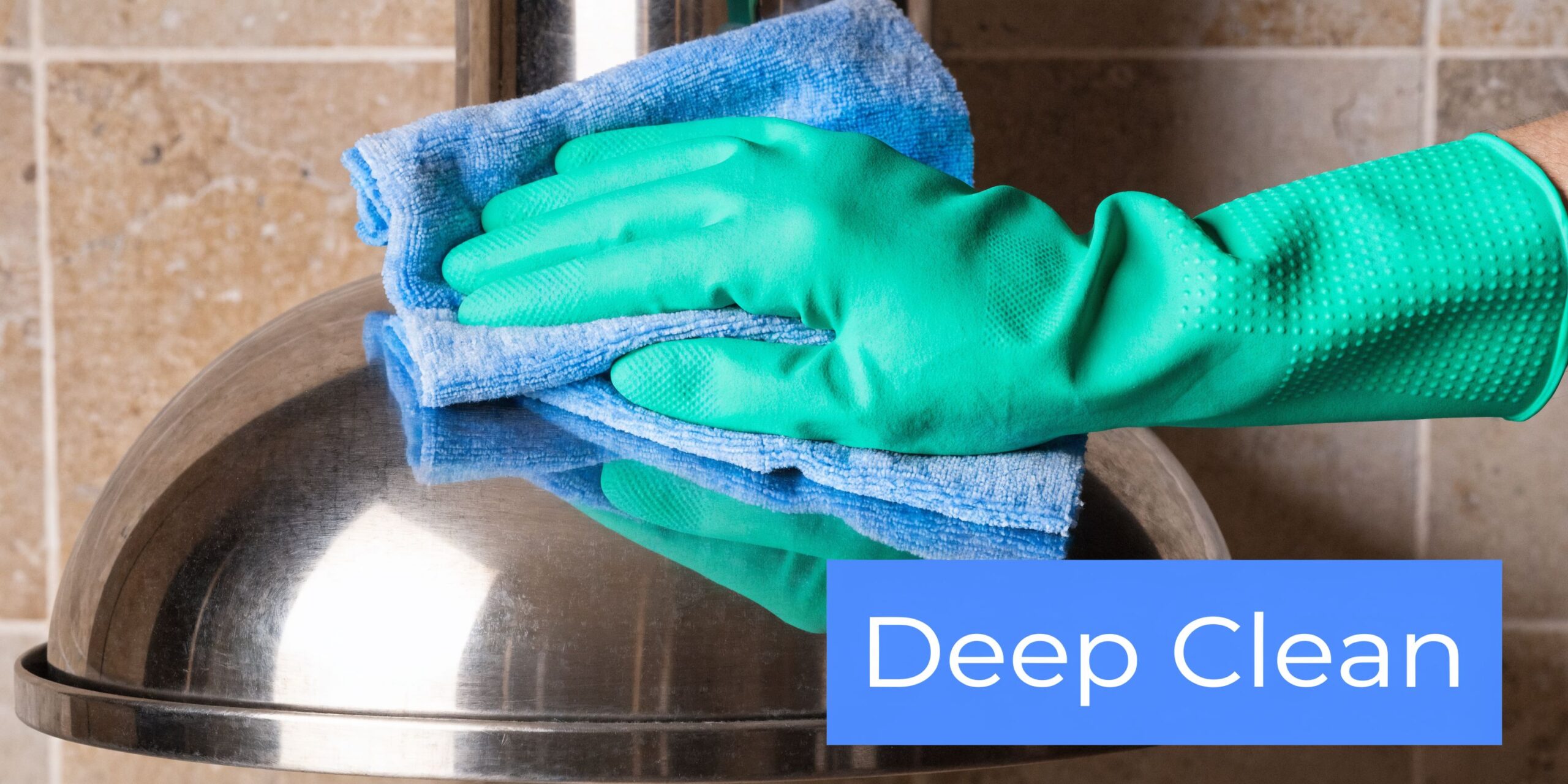 A gloved hand wearing a green rubber glove wipes down a shiny stainless steel range hood.