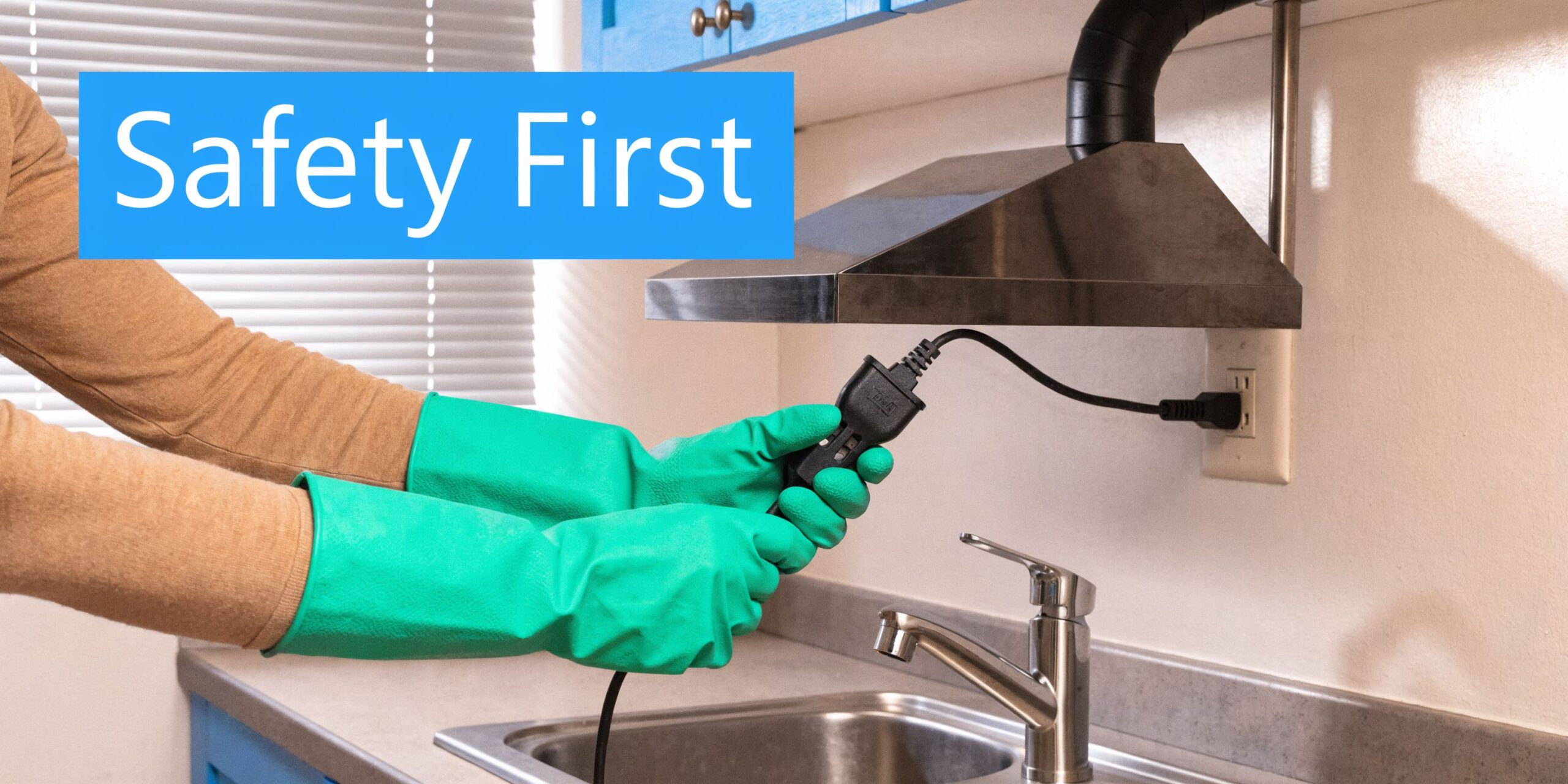 A person wearing green rubber gloves about to unplug a kitchen range hood near a sink.