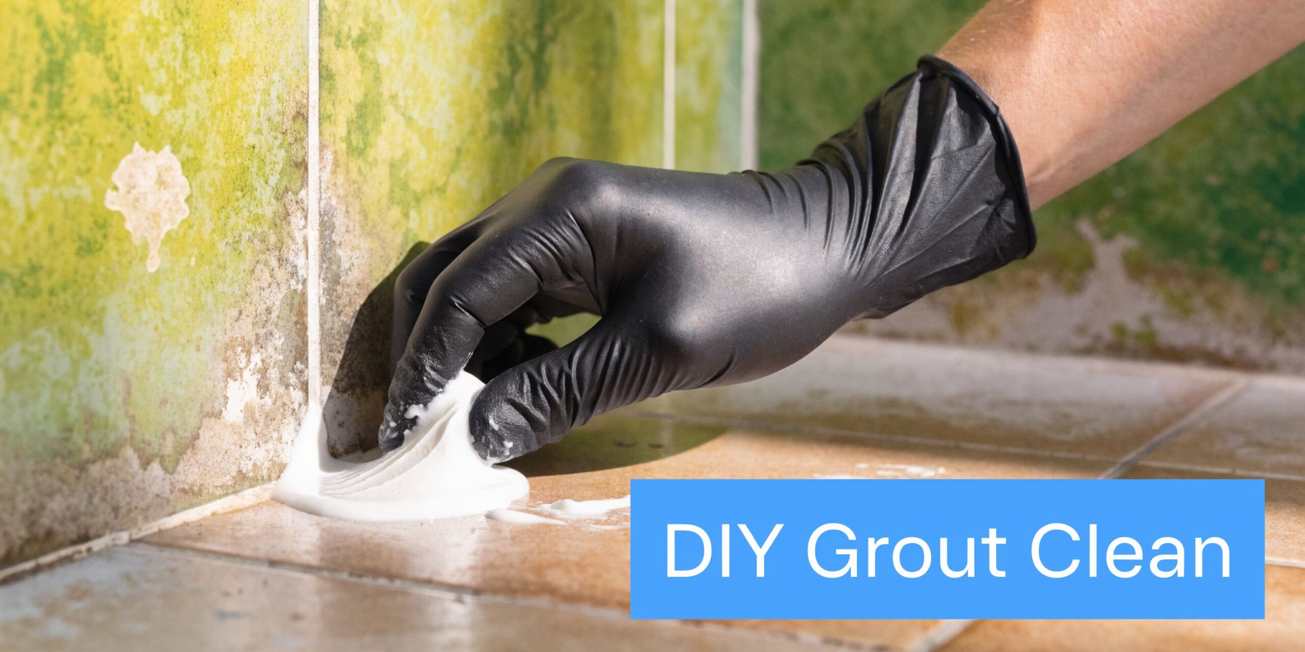A person wearing a black glove applying a cleaning paste to dirty bathroom floor tile grout.